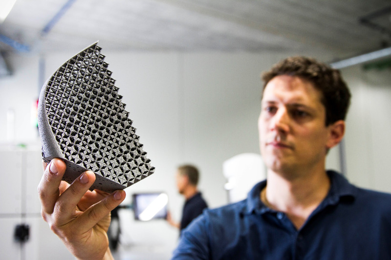 A man holding a 3D printed part made of metal